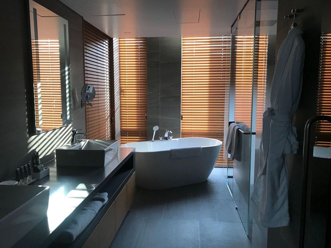 Stylish bathroom suite with a standalone bathtub and wooden blinds at Dongdaemun Novotel Ambassador Hotel.